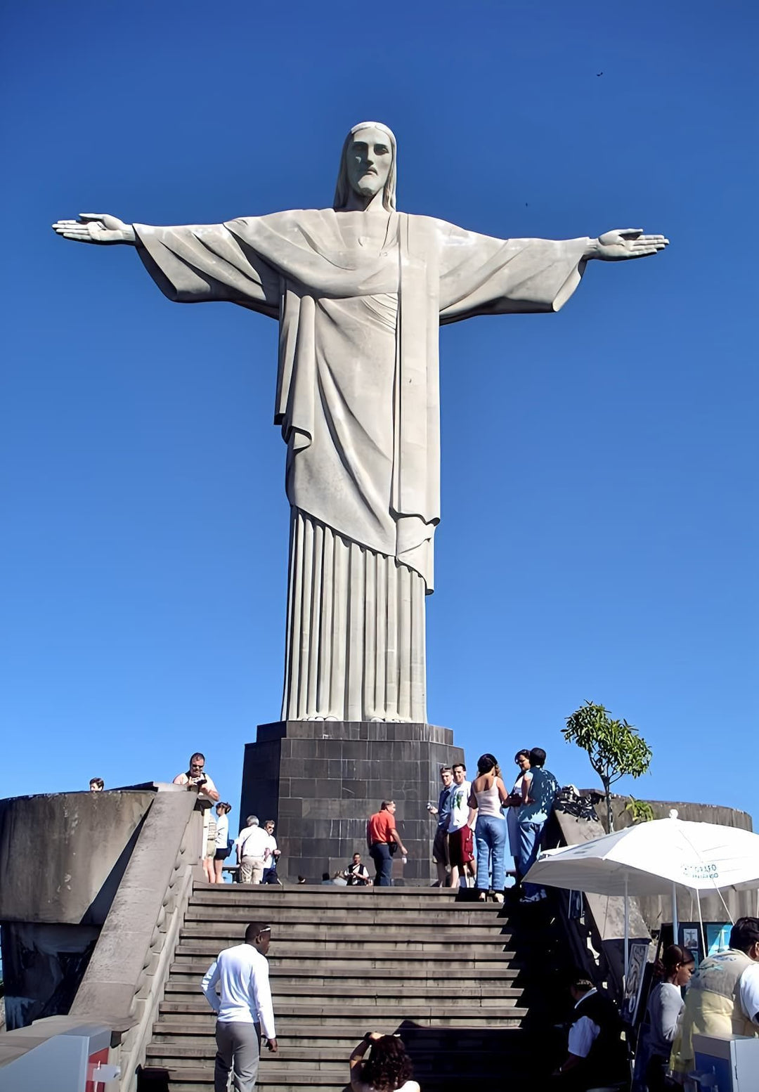 Awed individuals stand before Christ the Redeemer, emotions stirred by the colossal statue, a spiritual encounter etched in hearts.