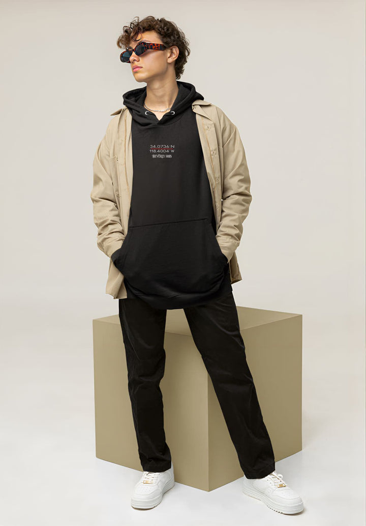 The image depicts a male individual wearing an oversized black hoodie, positioned next to a cubic object.