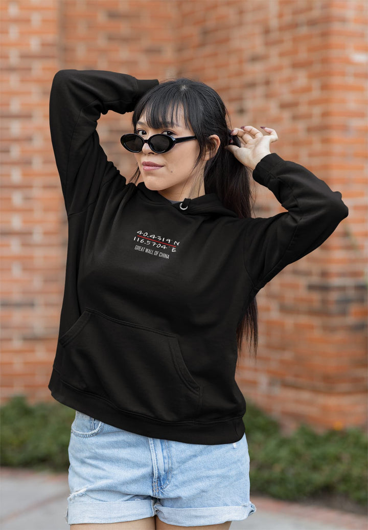 A woman wearing a black hoodie and modeling a long ponytail.