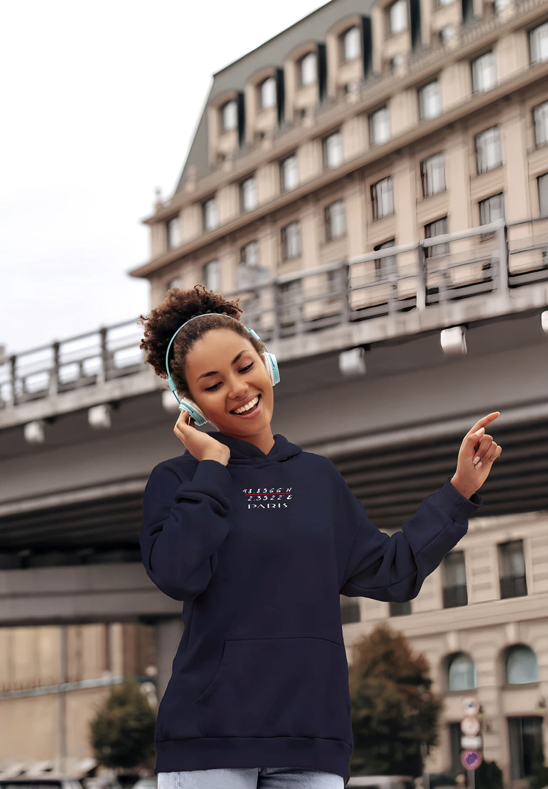 The woman's radiant smile enhances her blue Paris pullover sweater, which contrasts with her contemporary headphones.