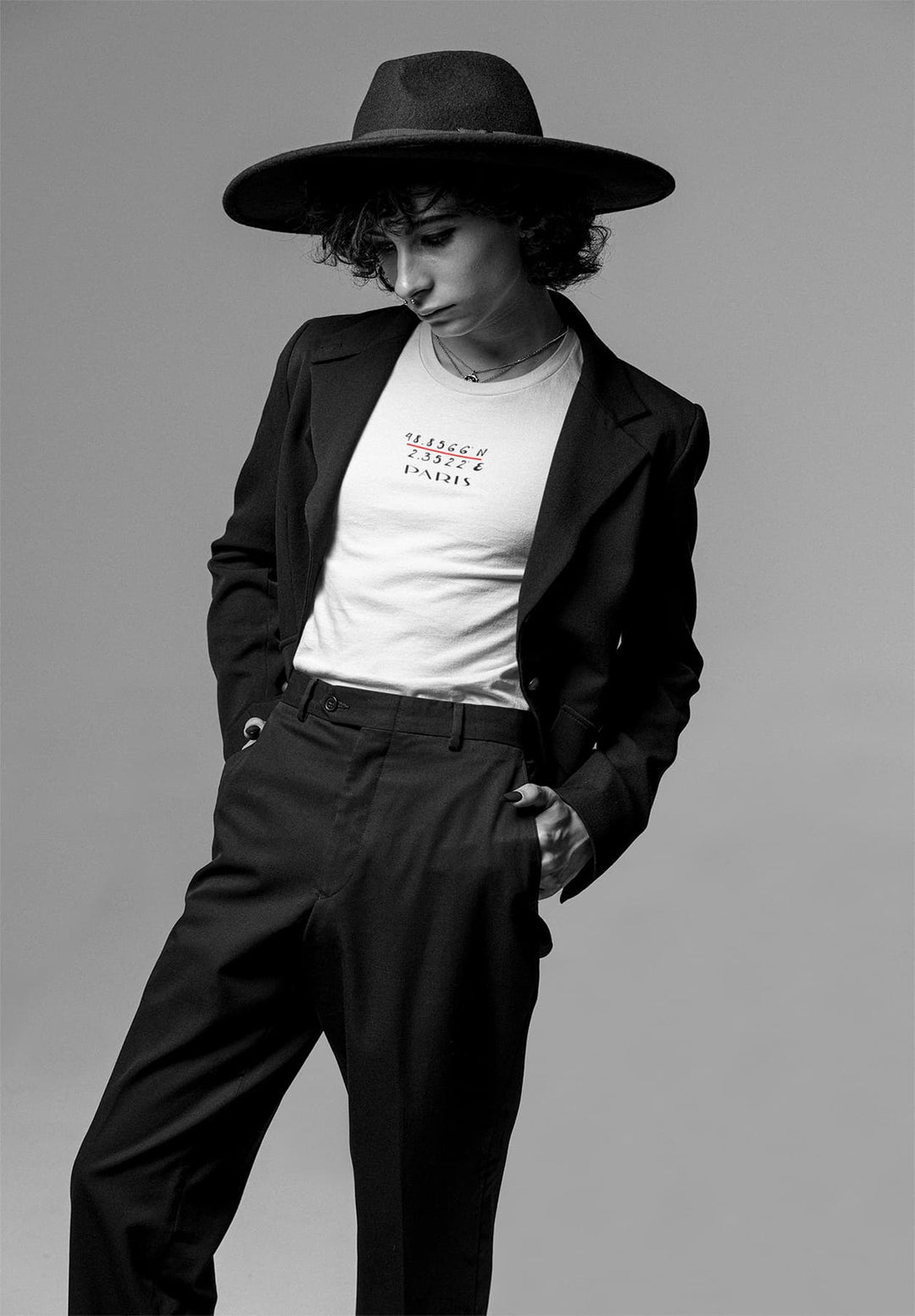 With a hat atop his head, he wears a white Paris t-shirt, embodying the spirit of adventure and romance.