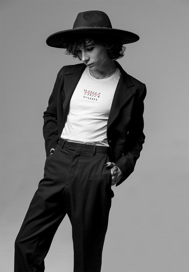 With a hat atop his head, he wears a white Paris t-shirt, embodying the spirit of adventure and romance.