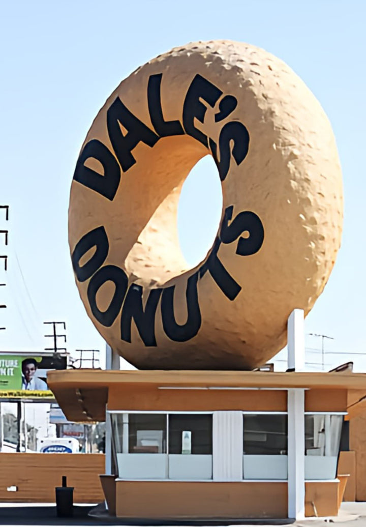 A donut shop called Dales Donuts has a huge donut perched on the roof of it.