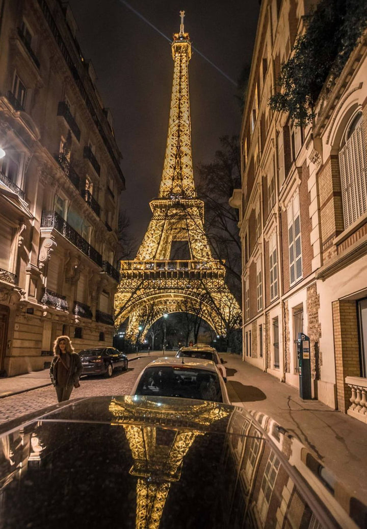 The Eiffel Tower serves as the backdrop for a parked car.