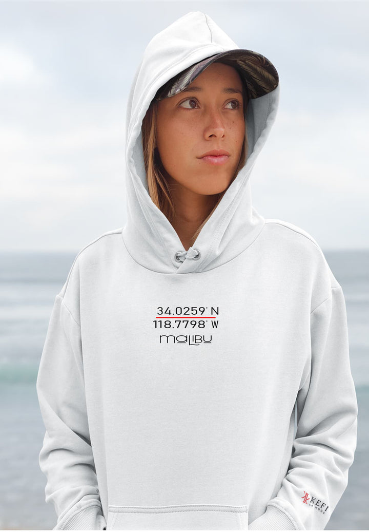 With the Malibu logo on her white hoodie, the woman embodies a sense of coastal appreciation and laid-back elegance.