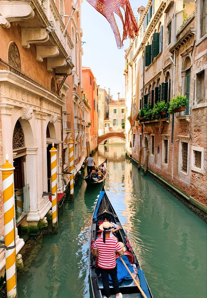 In Venice, Italy, a gondolier can be seen navigating his gondola through one of the city's small canals.