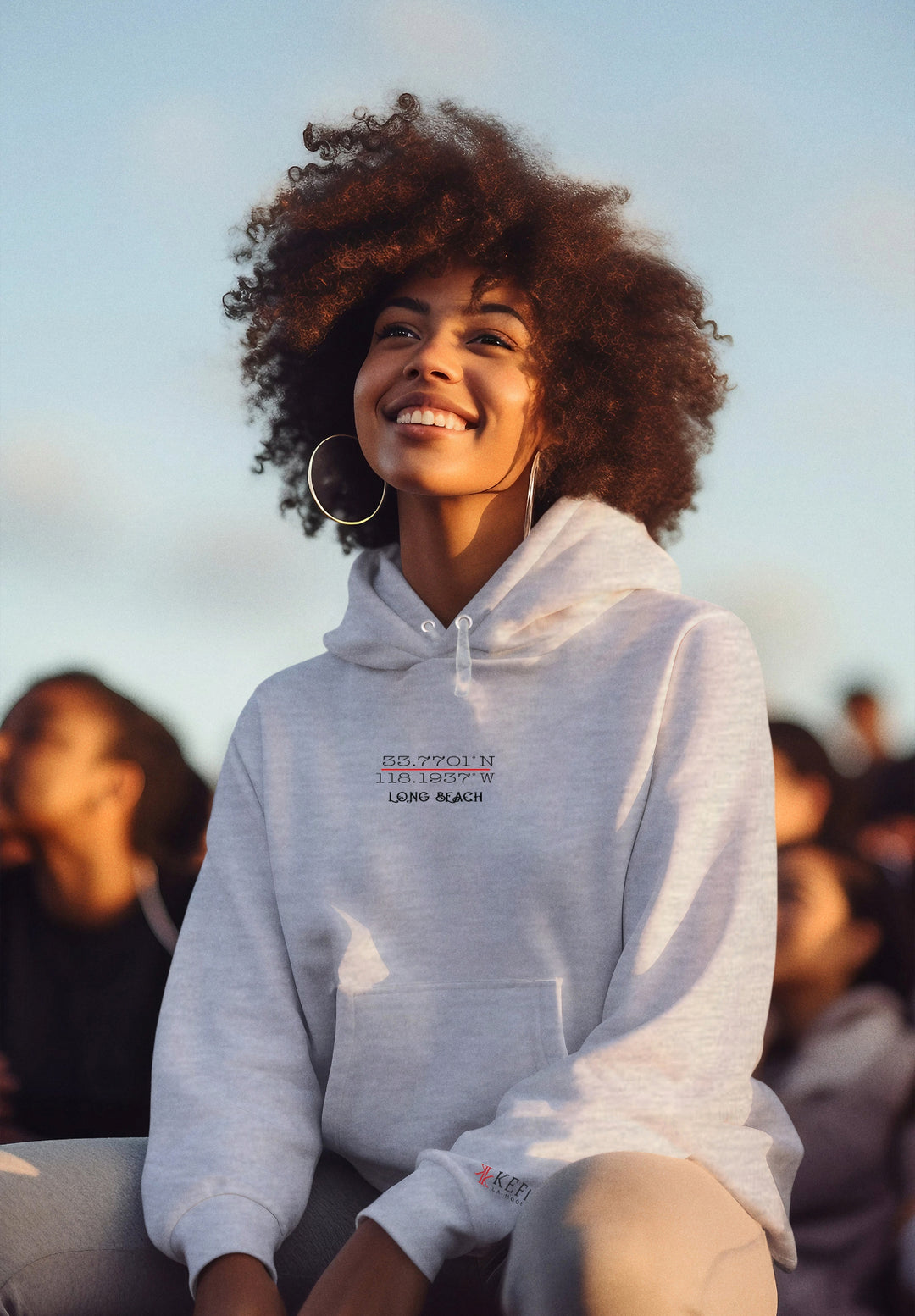 With her beaming smile, the woman wearing a gray hoodie exudes an air of cheerful contentment and relaxed elegance.