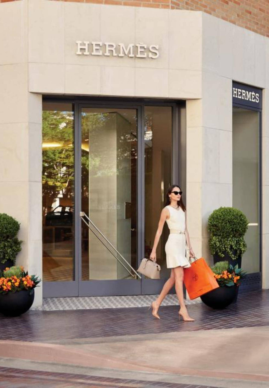 A woman adorned in a fashionable garment departs from the shopping center, clutching numerous packages, exuding the delight of discovering newfound treasures.