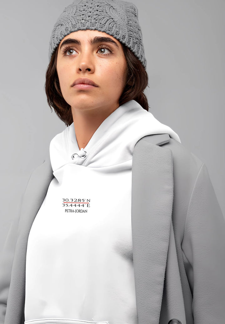 The lady's gray cap serves as a stylish accent to her white Petra sweatshirt with a touch of urban sophistication.