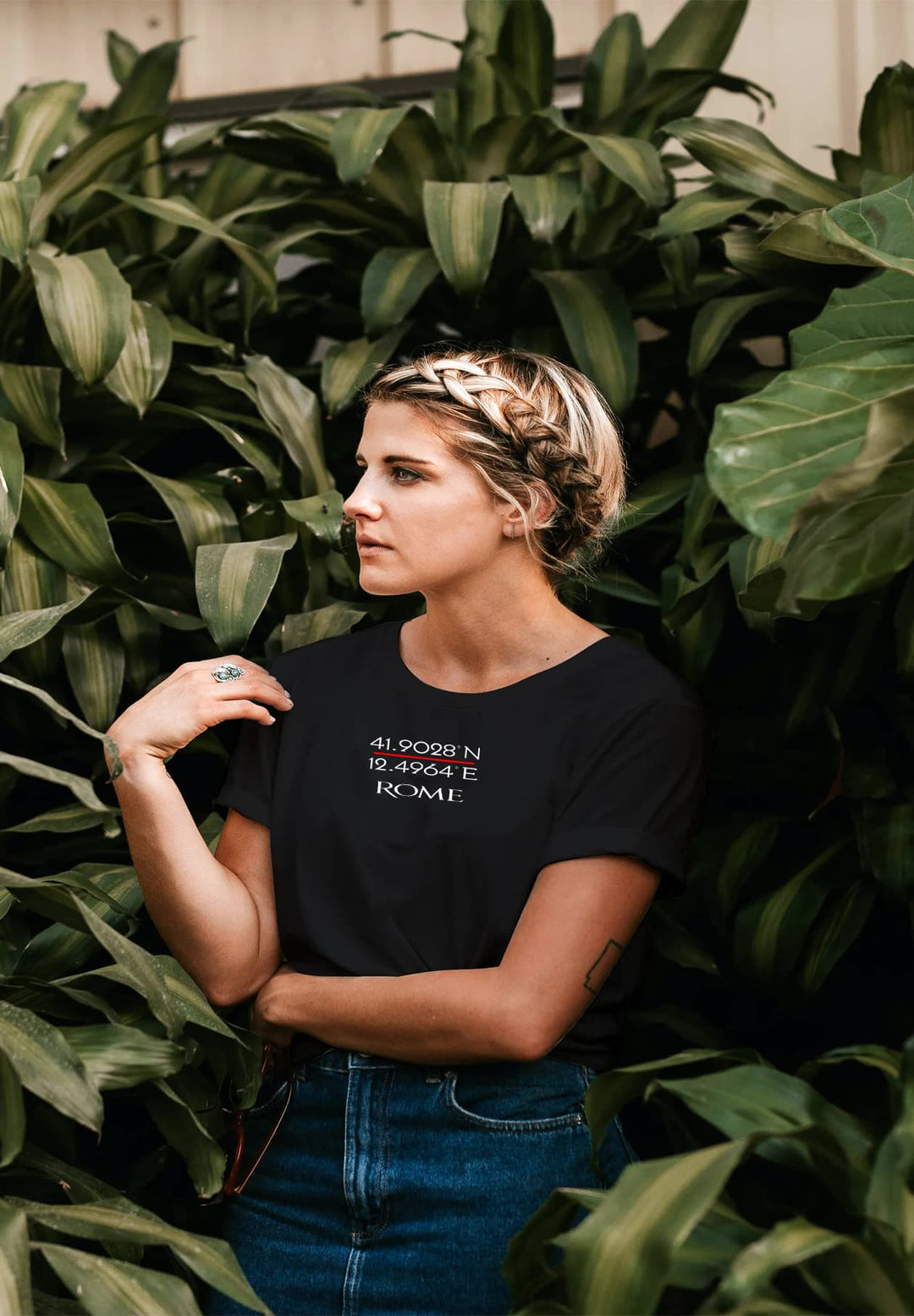 Standing amidst plants in her black Rome tee, the lady savors moments of nature's tranquility, memories intertwined with foliage.