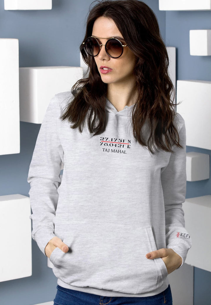 In the subtle elegance of a gray hoodie, a long-haired woman stands with the timeless allure of sunglasses.