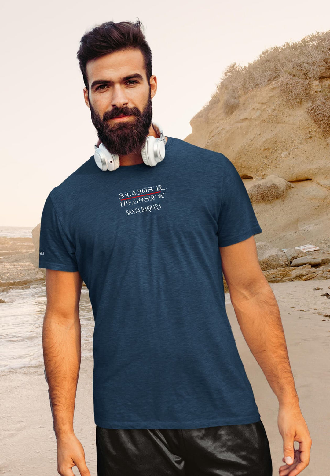 With headphones draped, he savors moments, his blue tee a companion to seaside melodies and cherished memories.