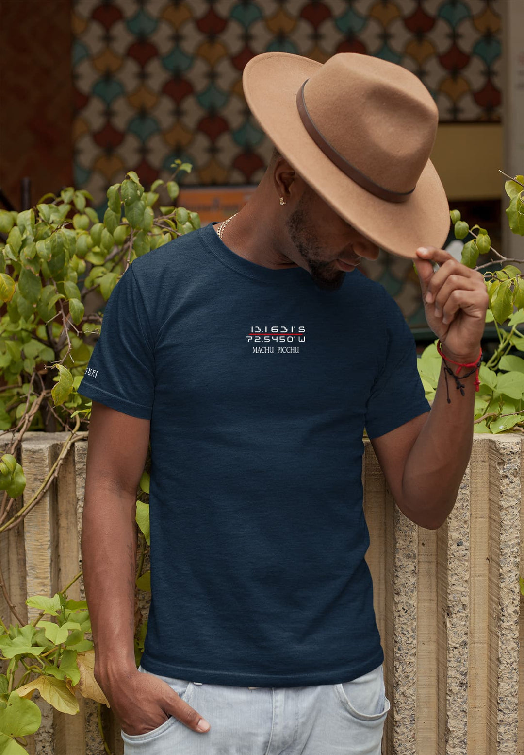 Against the fence, his hat shading memories, the blue Machu Picchu tee echoes tales of adventure and wonder.