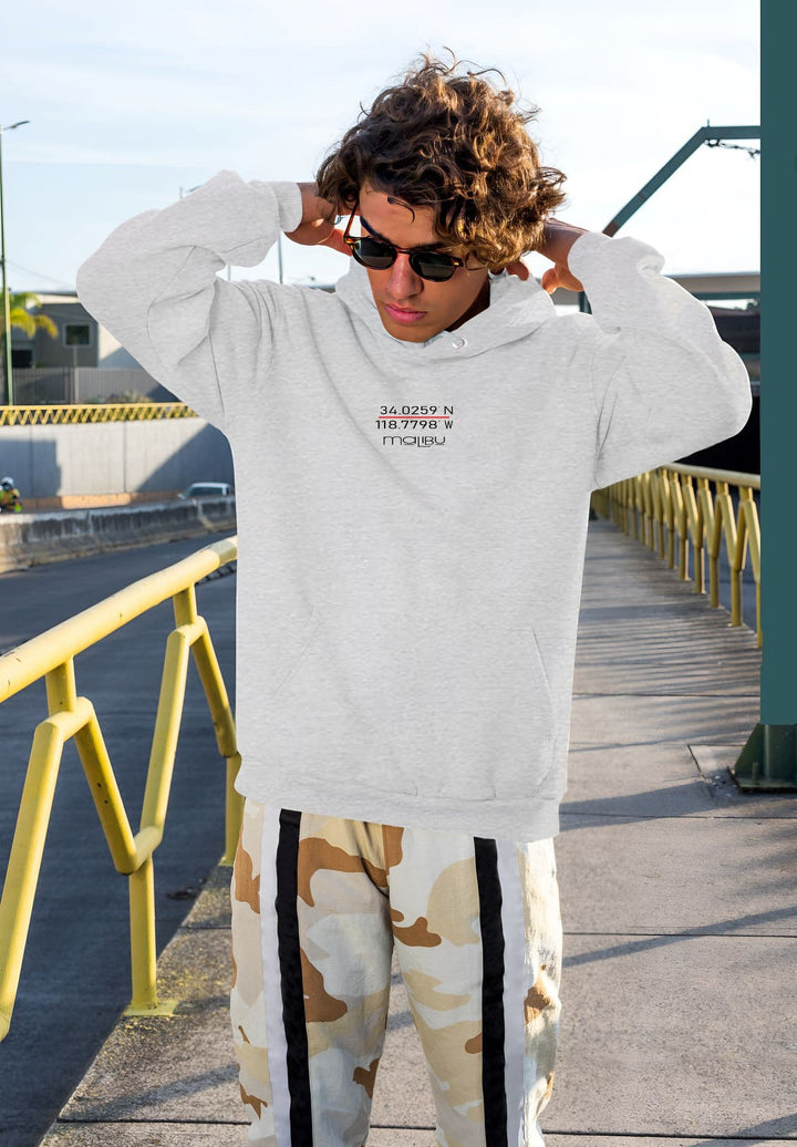 Standing tall, the man confidently rocks a gray sweatshirt paired with camo pants, creating a stylish ensemble.