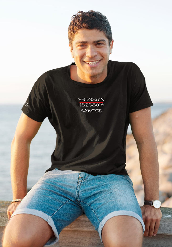 Sitting on the wooden ledge by the ocean in a black tee, he savors moments of tranquility and introspection.