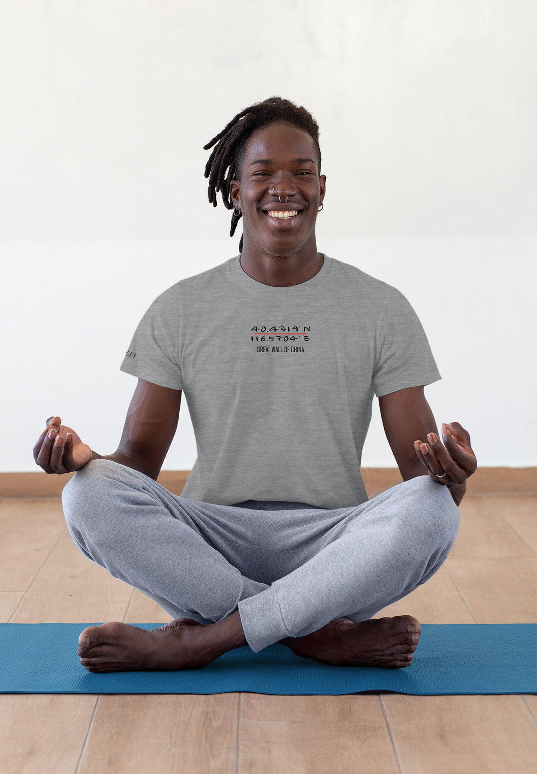 On the yoga mat, the man in a gray tee sits, a serene smile unveiling the peaceful emotions within.