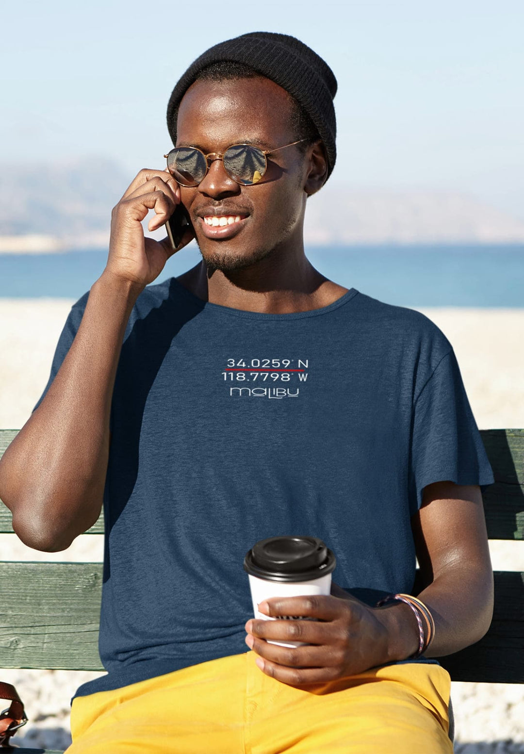 In his blue tee, he sits on the bench by the beach, sharing stories that echo laughter and warmth.