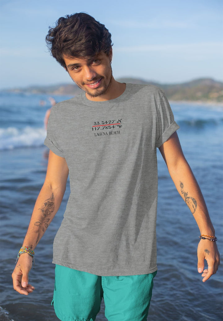 Standing in the water, gray tee clinging, he smiles—a moment etched in seaside joy, where waves echo laughter.