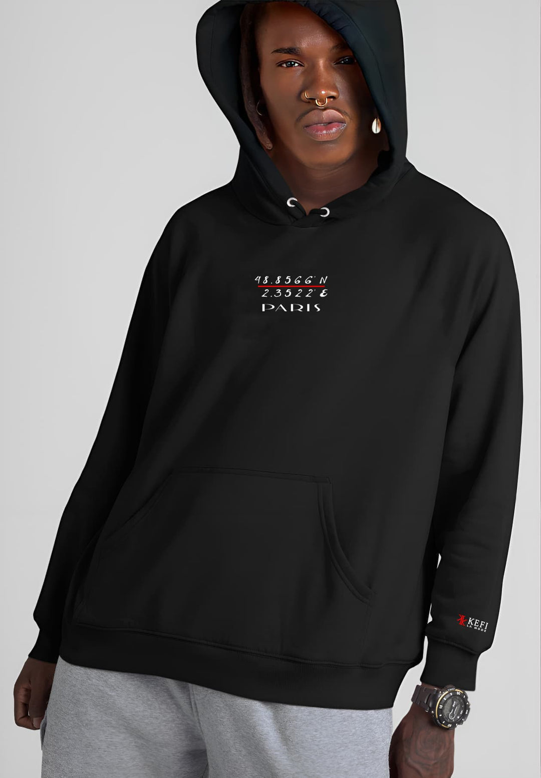 The combination of gray sweatpants and a fashionable black Paris Hoodie sweatshirt elevates the young man's fashion game.