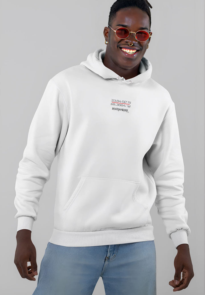 With a blend of comfort and street style, the young man elevates his outfit by wearing a white Redondo Beach hoodie and sleek red sunglasses.
