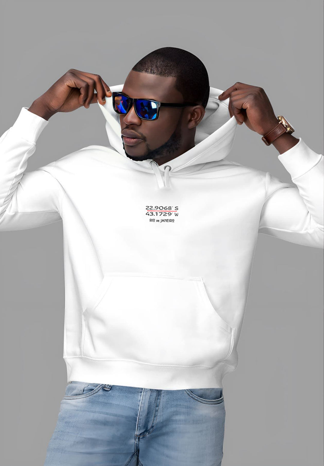 With a blend of comfort and street style, the young man elevates his moment by wearing a white Rio de Janeiro hoodie and a sleek pair of sunglasses.