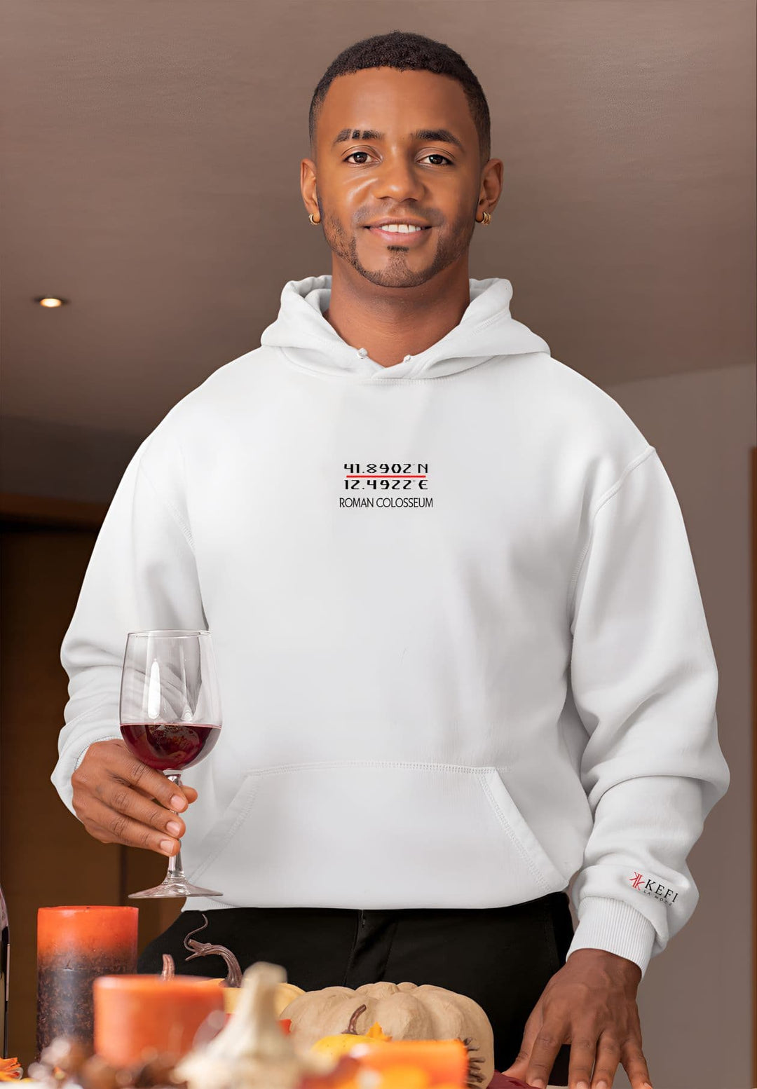 The man stands confidently, embracing a pullover white hoodie adorned with the timeless Roman Colosseum GPS coordinates design.