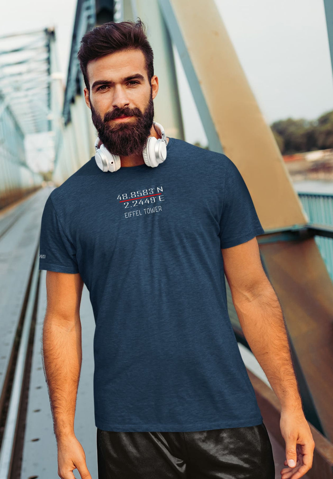 Lost in melodies, the bearded man on the bridge wears emotions like a blue tee, resonating with life's rhythm.