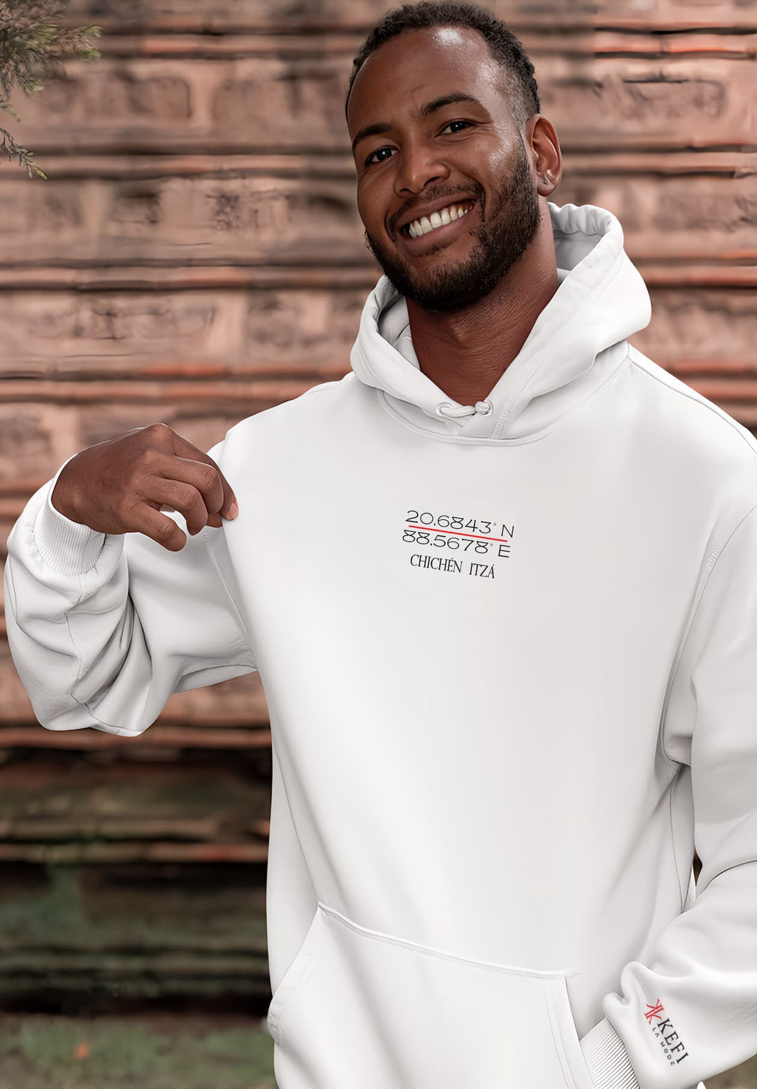 A man with black hair stands wearing a white hoodie, a portrait of joy and personal style.