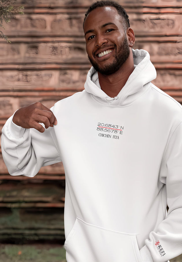 A man with black hair stands wearing a white hoodie, a portrait of joy and personal style.