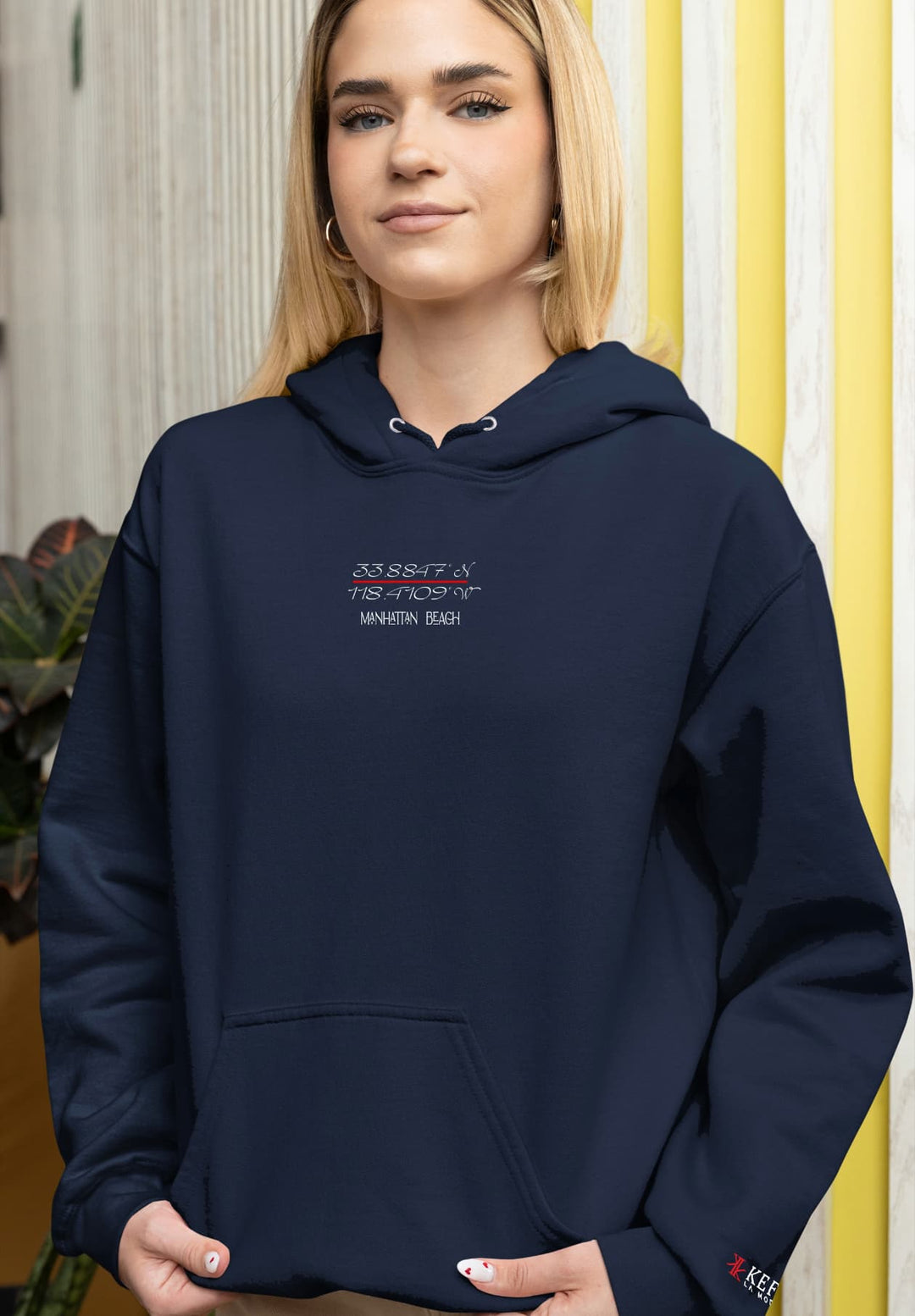 The image captures the woman's poise and ease as she effortlessly poses in the white Manhattan Beach hoodie.