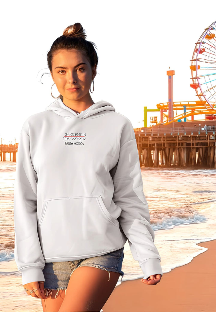 A beautiful girl in a white hoodie graces a Santa Monica Beach sunset. 