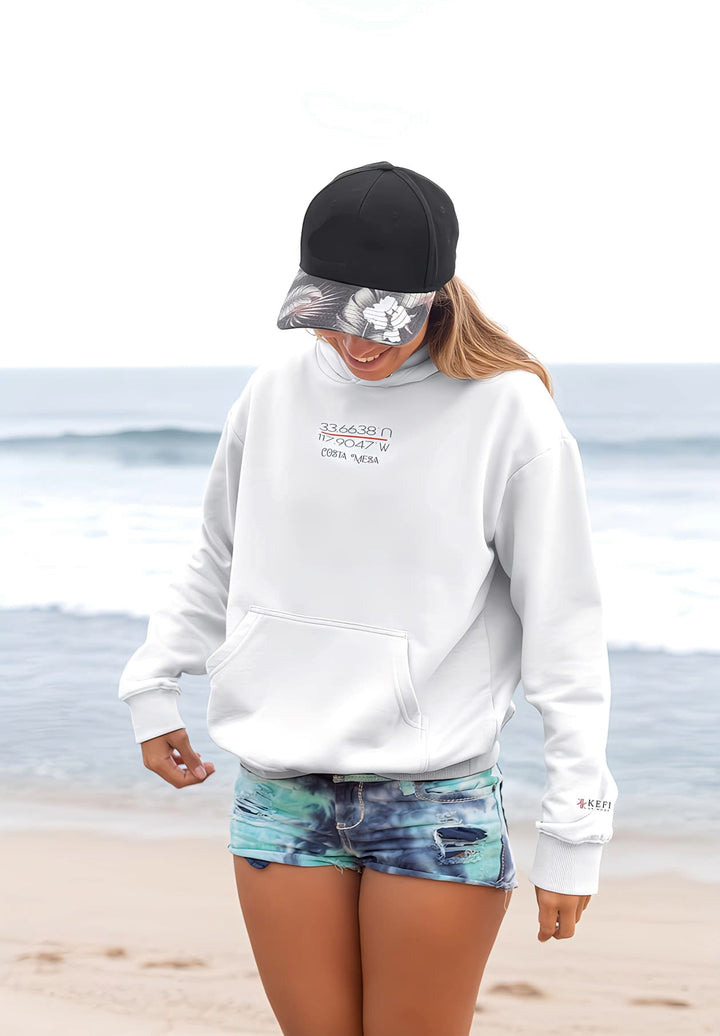 As the beach waves danced in the background, the woman's joyful smile and her choice of a white pullover hoodie combined to create a picture-perfect fashion moment by the shore.