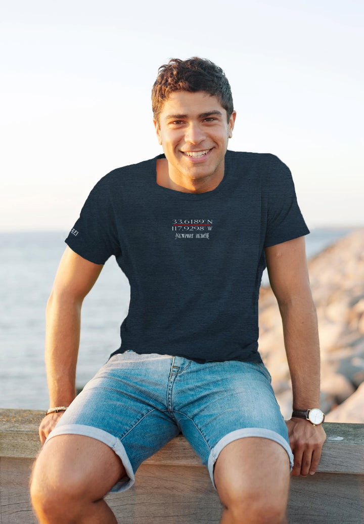 By the ocean's serenity, the smiling man in a blue tee radiates joy, his happiness mirroring the endless horizon.