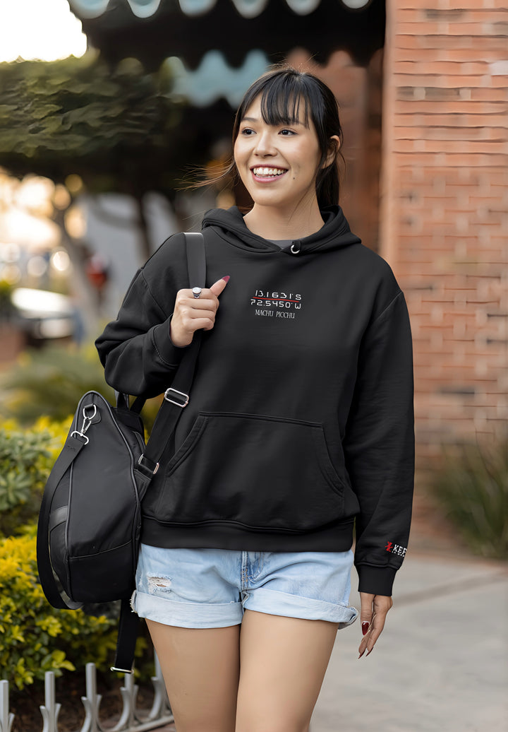 Embracing the spirit of adventure, the smiling woman dons the Machu Picchu black pullover hoodie and carries a bag.
