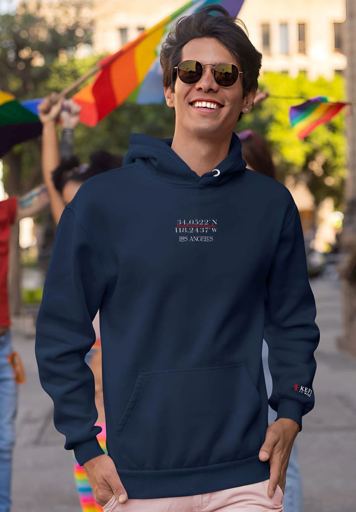 A man attending the pride parade while decked out in a blue hoodie and sunglasses and celebrating.