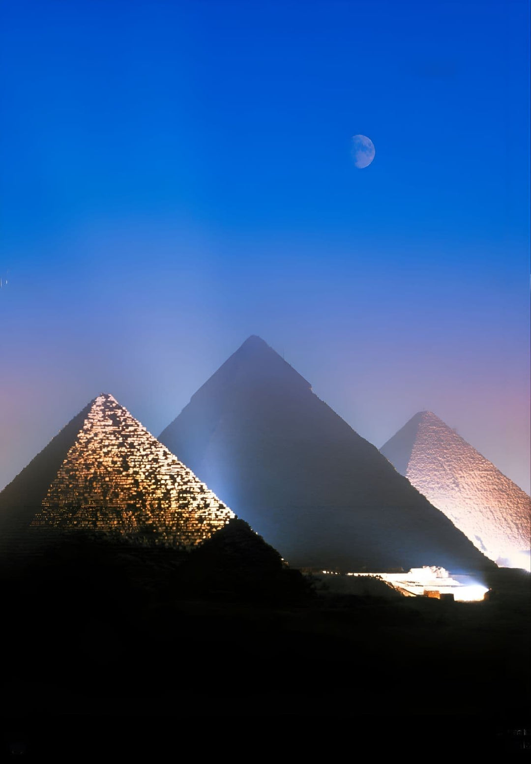 At night in Egypt, the three pyramids of Giza are illuminated by lights.