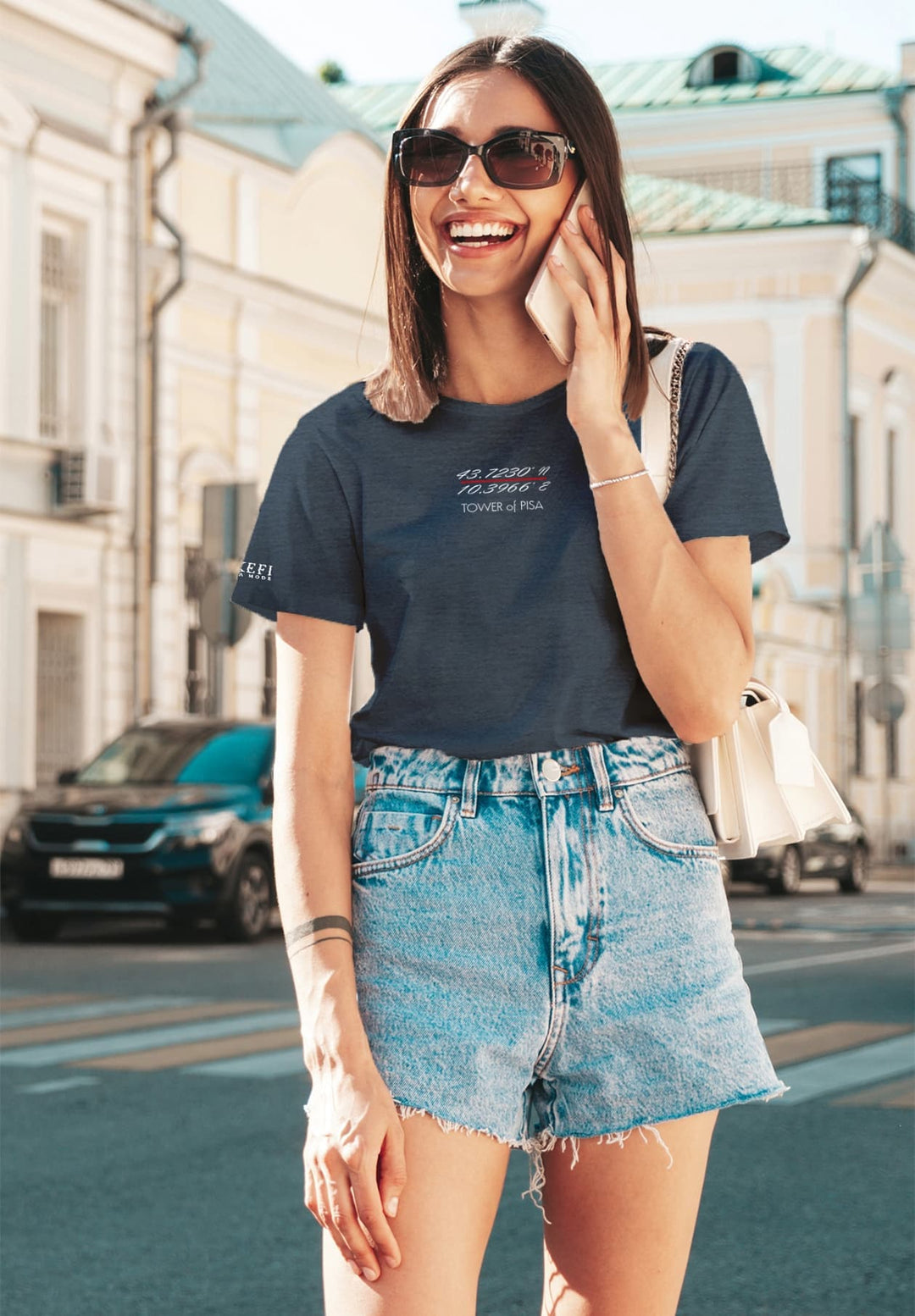 Captured in a moment, a woman stands engaged in her blue T-shirt, navigating her world through the device in her hands.