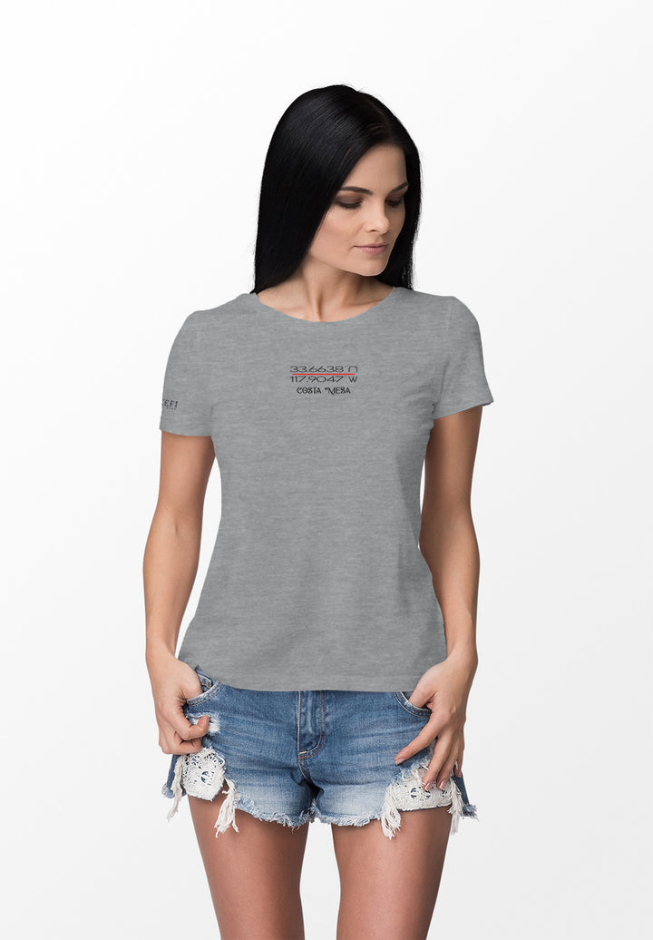 A stylish woman in a gray t-shirt, her hands in her pockets, creates comfort and beauty with ease and honesty.
