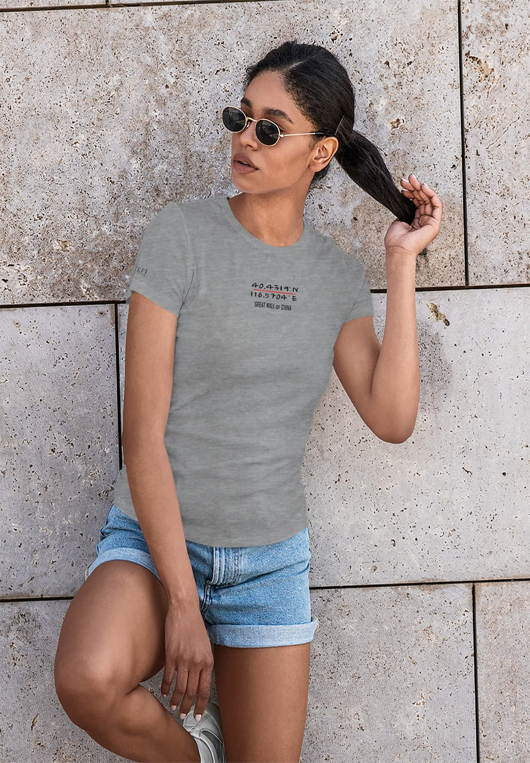a woman in her chic gray shirt, confidently leaning against a wall with sunglasses, captures a sense of timeless style and self-assured elegance.