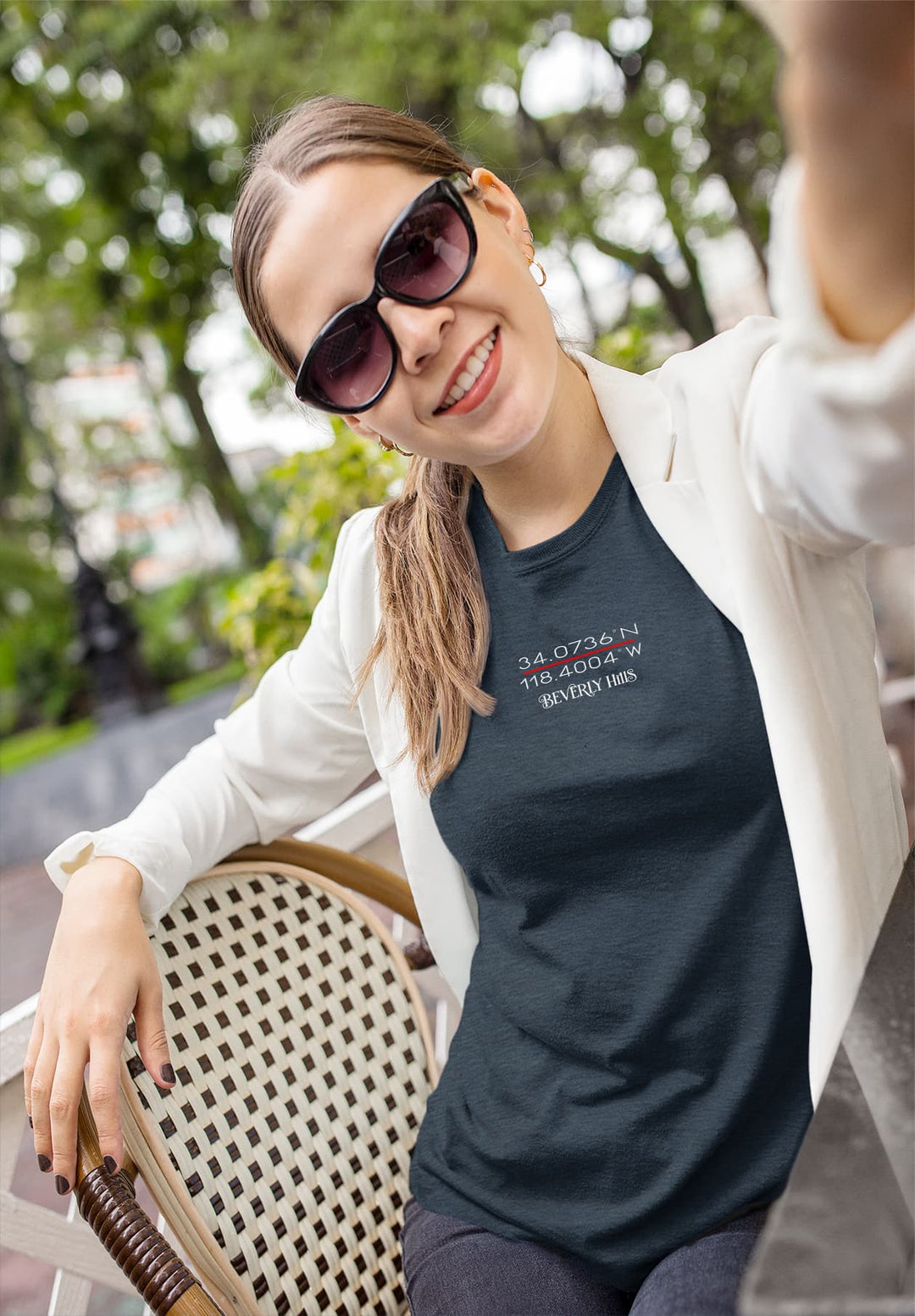 Basking in the outdoor ambiance, a woman sits on a chair in a captivating blue shirt and blazer, creating a picturesque moment of style.