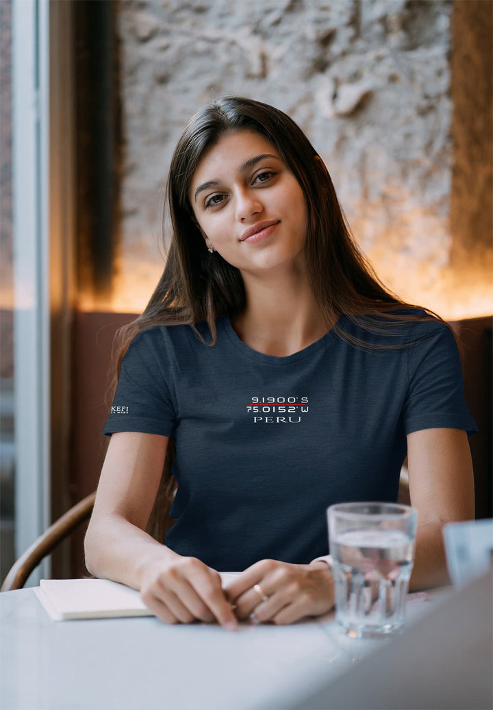In the soft glow, she sits, a tranquil moment painted in blue t-shirt, a serene tableau of contemplation with a glass of water.