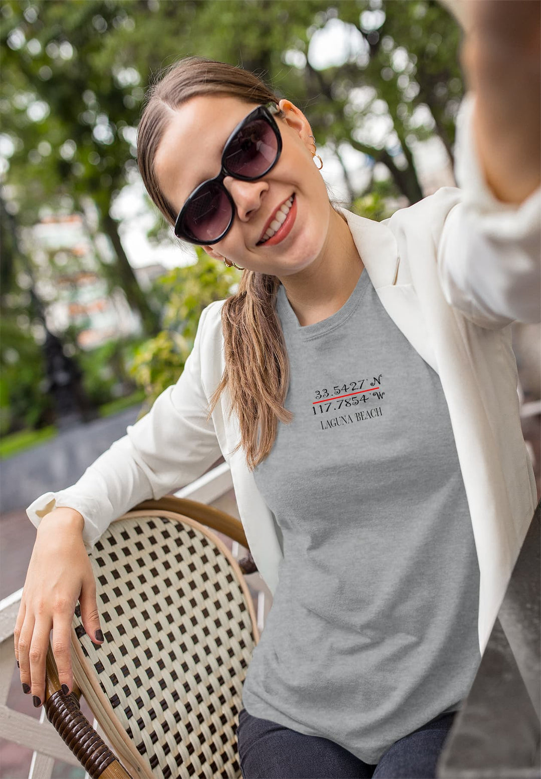 Amidst the open air, a woman sits tranquilly on a chair, wrapped in the comfort of a gray T-shirt, a moment of peaceful serenity.