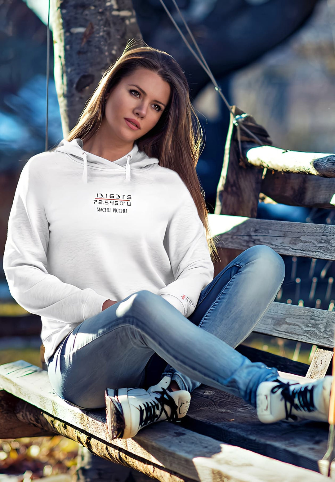 The gray Machu Picchu hoodie becomes a symbol of her appreciation for cultural heritage as the woman sits on the rustic bench.