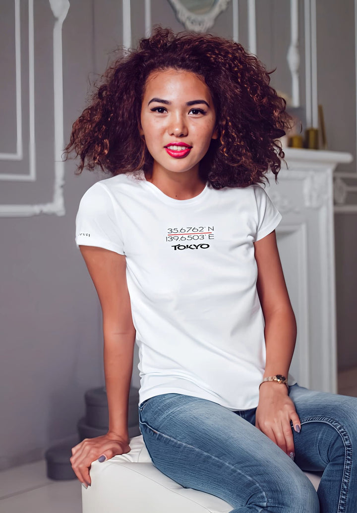 Elegantly perched on a white stool, she radiates simplicity and grace in her crisp white T-shirt, embodying timeless style.