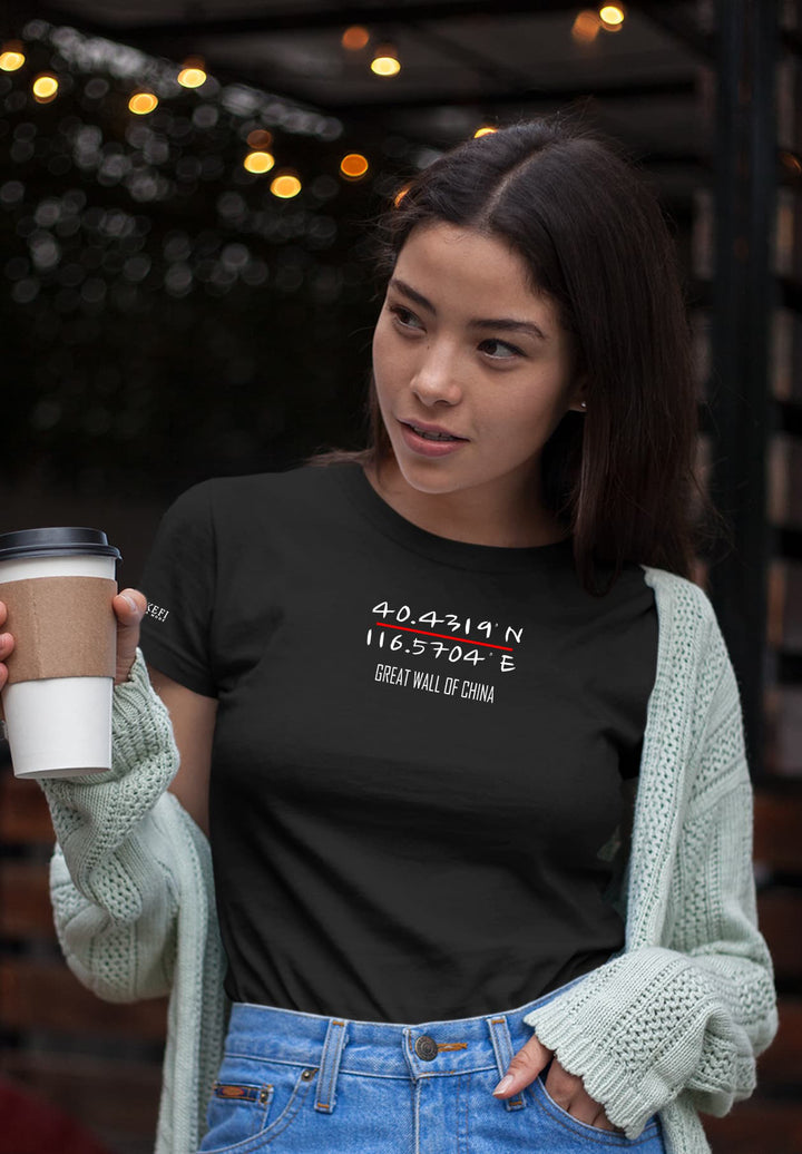 A woman has an air of effortless elegance as she confidently holds a cup of coffee, dressed in a stylish black T-shirt.