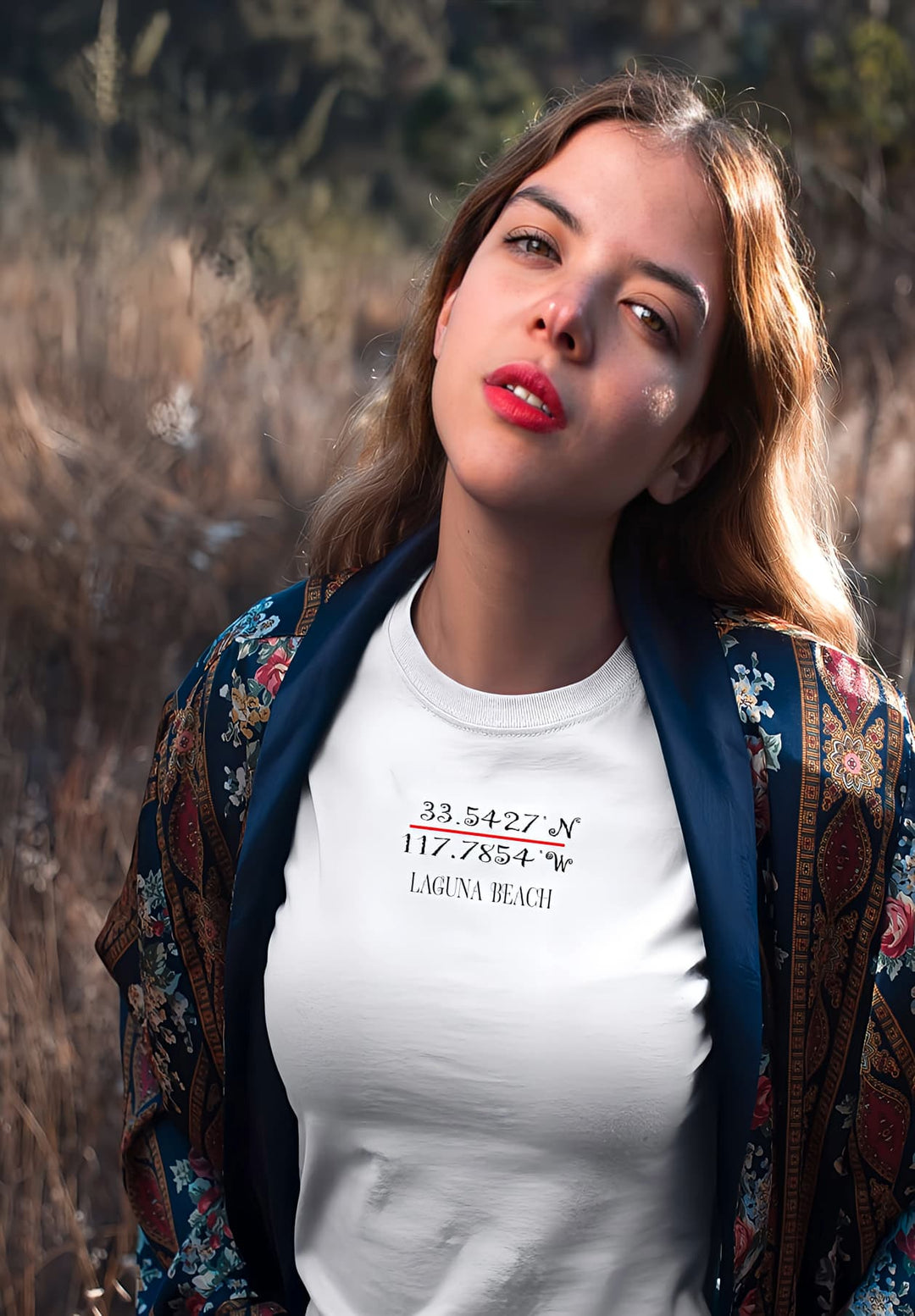 In the embrace of nature's canvas, a woman stands in a white T-shirt, a vision of serenity amidst the whispers of the field.