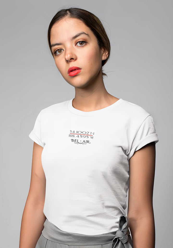 A picture of effortless beauty, the woman stands in a white logo T-shirt and dress pants, capturing a timeless moment.