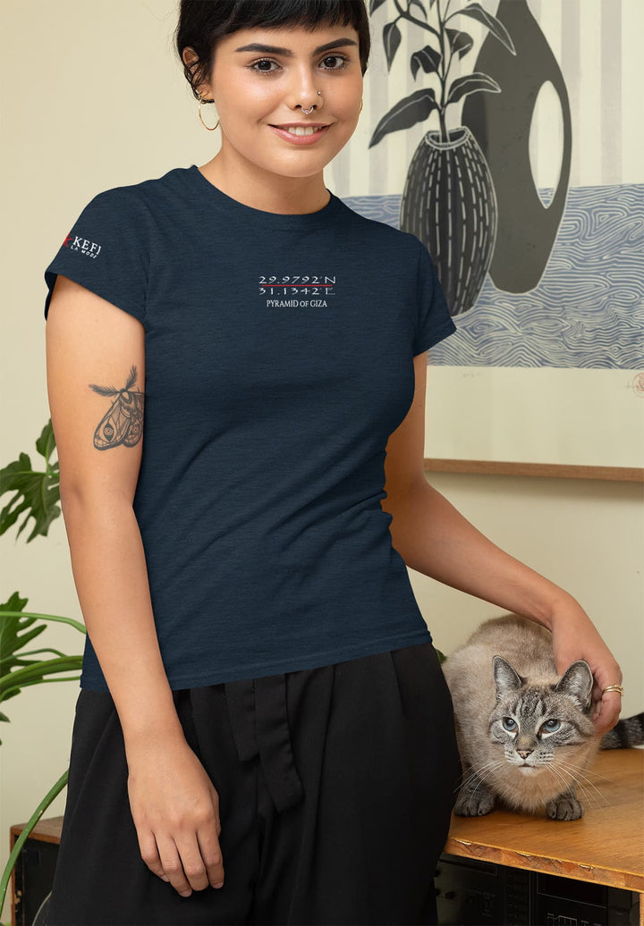 A lady caresses a cat resting on a table while wearing a casual blue T-shirt. 