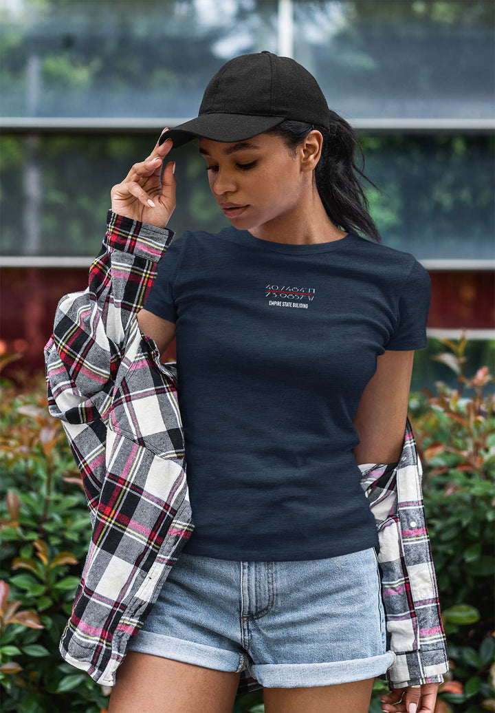 A self-assured woman stands tall, her black hat a chic accessory to her chic blue t-shirt. 