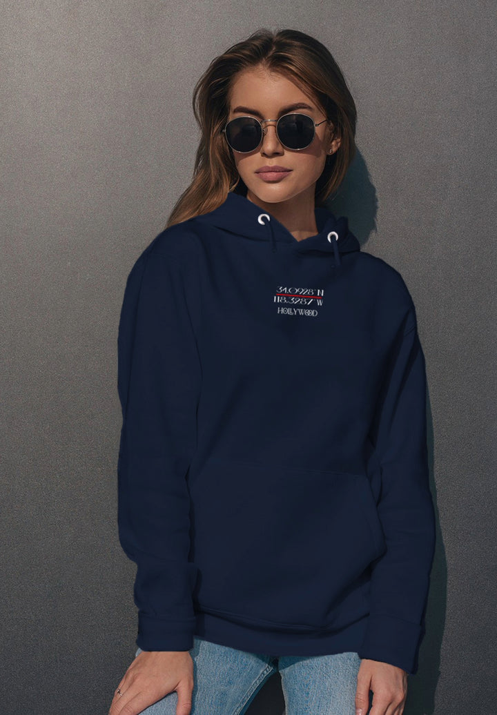 In her blue hoodie and sunglasses, the woman stands with poise, fashioning a memory of chic and timeless urban style.